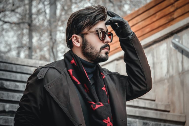 Homme aux cheveux bruns et avec une barbe qui descend des escaliers en hiver en portant des lunettes de soleil